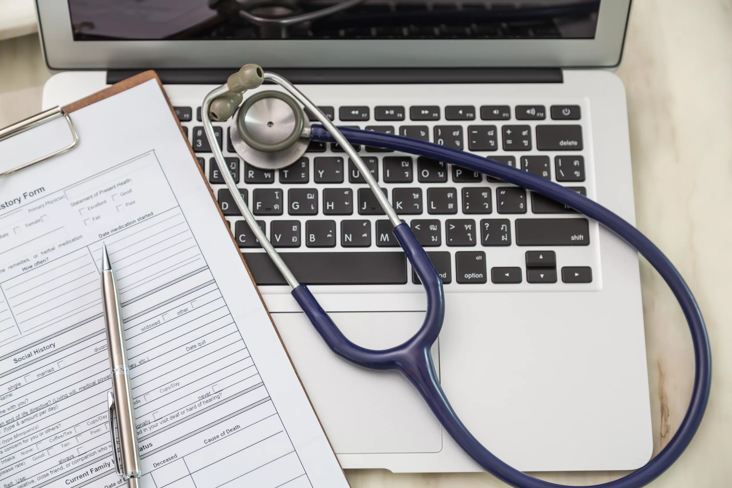 Stethoscope resting on a laptop next to a paper form.